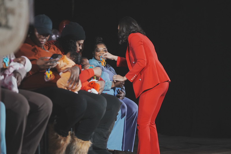 Detroit Mayor Mary Sheffield dressed in red passing out keys to two moms who are holding babies.