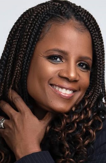 A smiling woman touching her braided hair