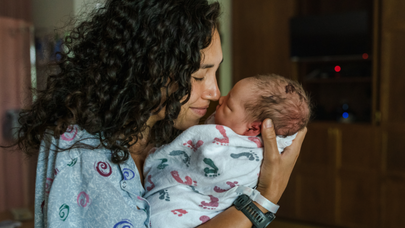 A woman with brown hair holding a baby, nose to nose
