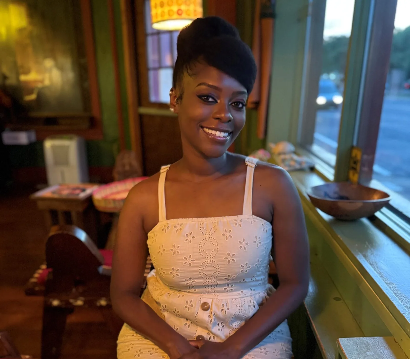 A woman in a white dress sitting at a table in a restaurant