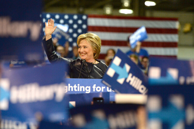 Hilary Clinton smiling and waving to an audience
