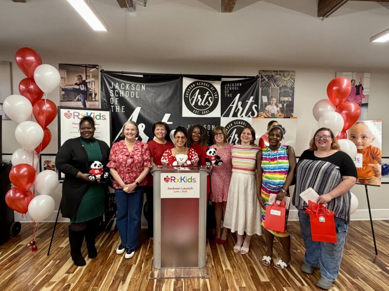 A group of 10 people standing behind an Rx Kids podium and smiling