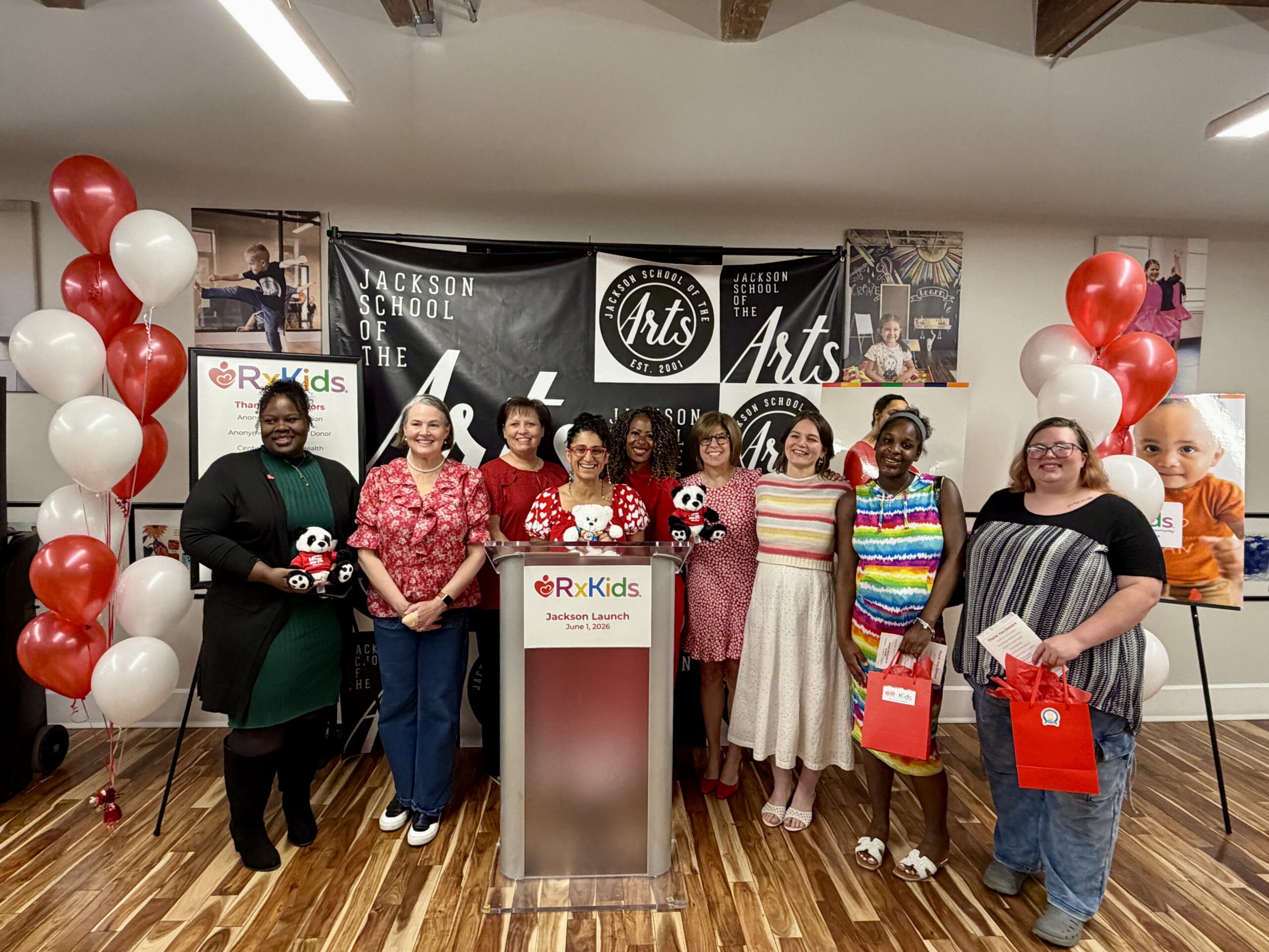 A group of 10 people standing behind an Rx Kids podium and smiling