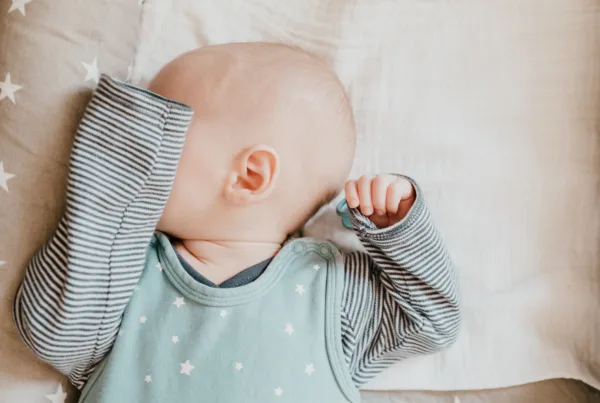 close-up of sleeping baby boy covering his eyes with his arm