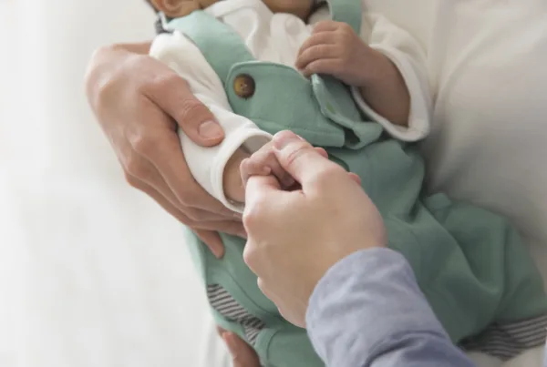 An adult hand holding a baby's hand