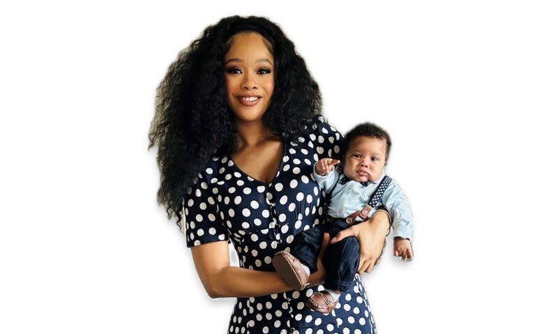 A mom in a black and white dress holding a baby