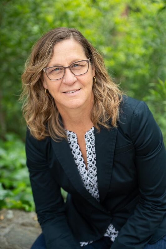 A woman in glasses and a dark suit smiling