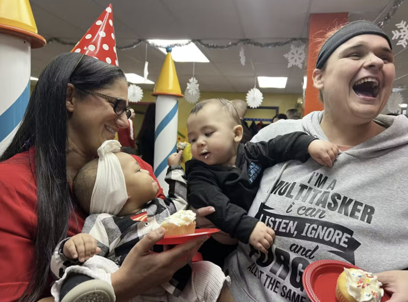 Two women holding babies at a birthday party